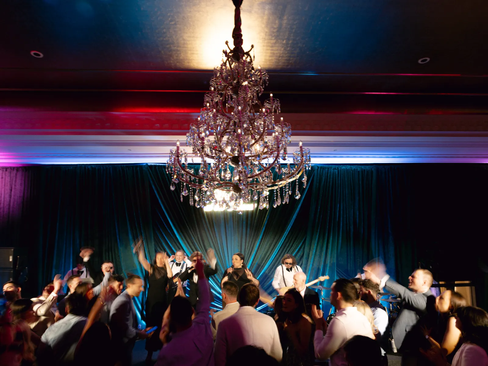Guests dancing beneath the chandelier as the band plays