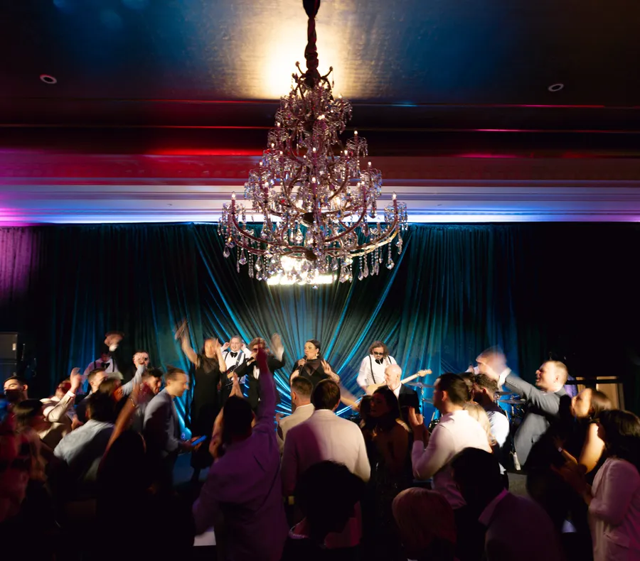 Guests dancing beneath the chandelier as the band plays