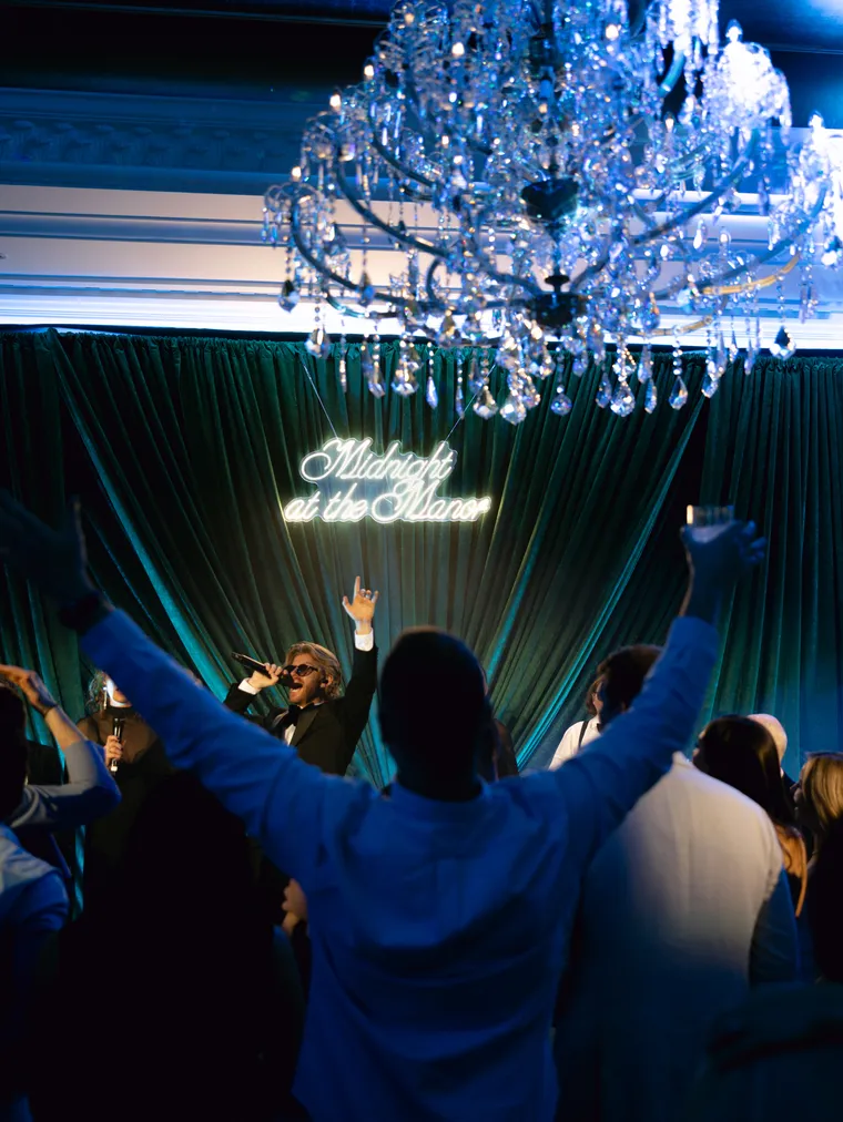 Guests dancing beneath the chandelier at a manor event